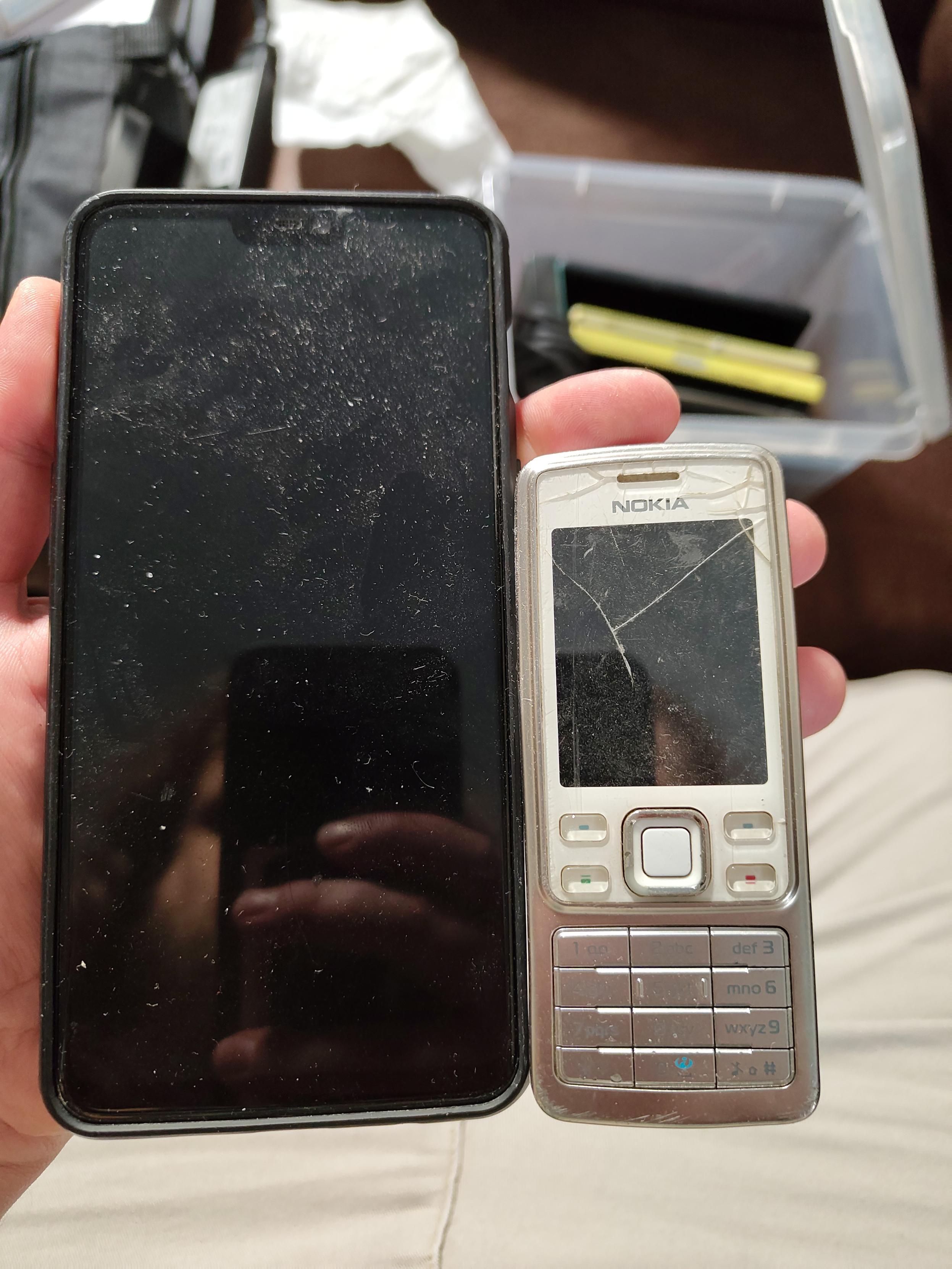 a black large oneplus 6 pro held next to the nokia 6300 on one hand. the entire nokia would probably fit 2.5x in the screen of the oneplus 6 pro