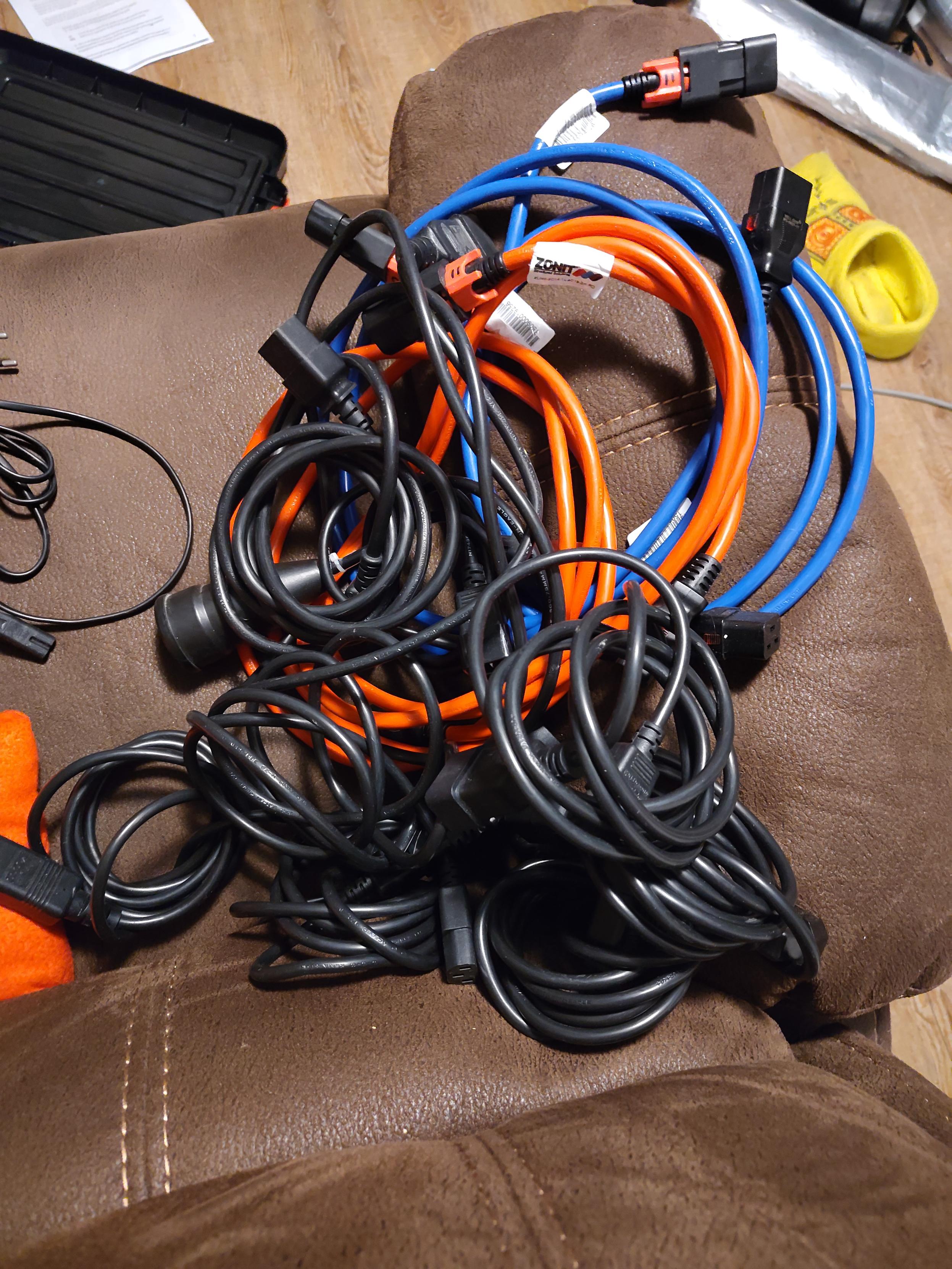 a bunch of rolled up cables on a brown leather couch. some of the cables are bright red or blue (2 of each color), the rest are black.