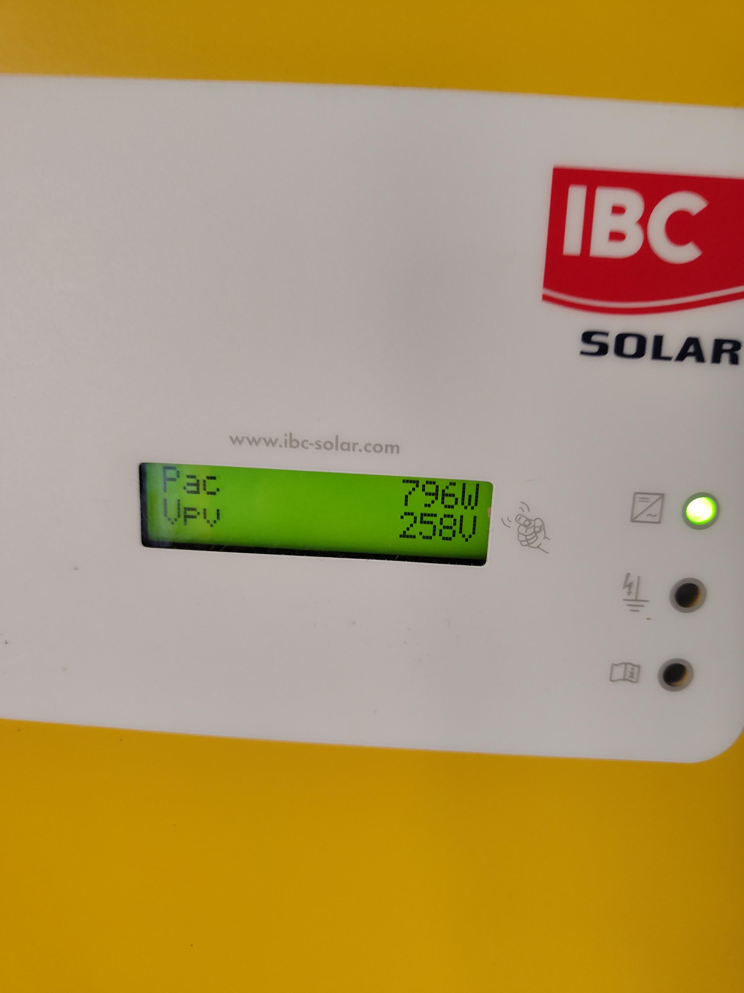 a photo of the white and yellow inverter front panel, showing 796W (Pac) and 258V (Vpv) on the screen. on the right there's three leds, the top green one is lit, and the "IBC Solar" logo is right above it.